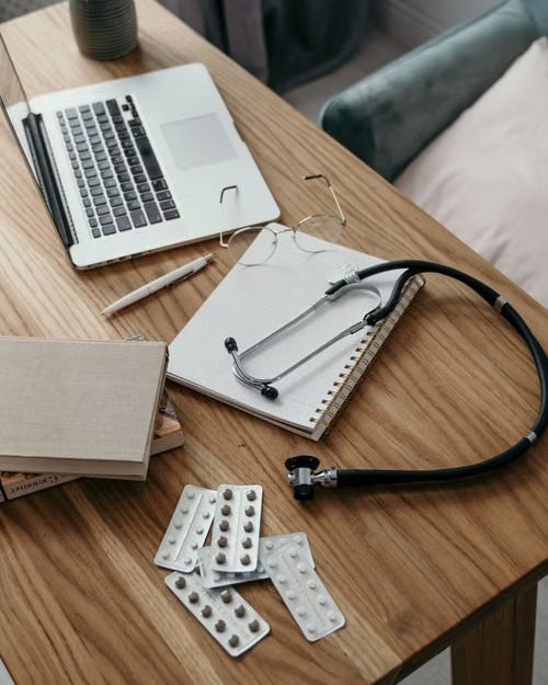Mesa de consulta médica con portátil, libreta y fonendoscopio