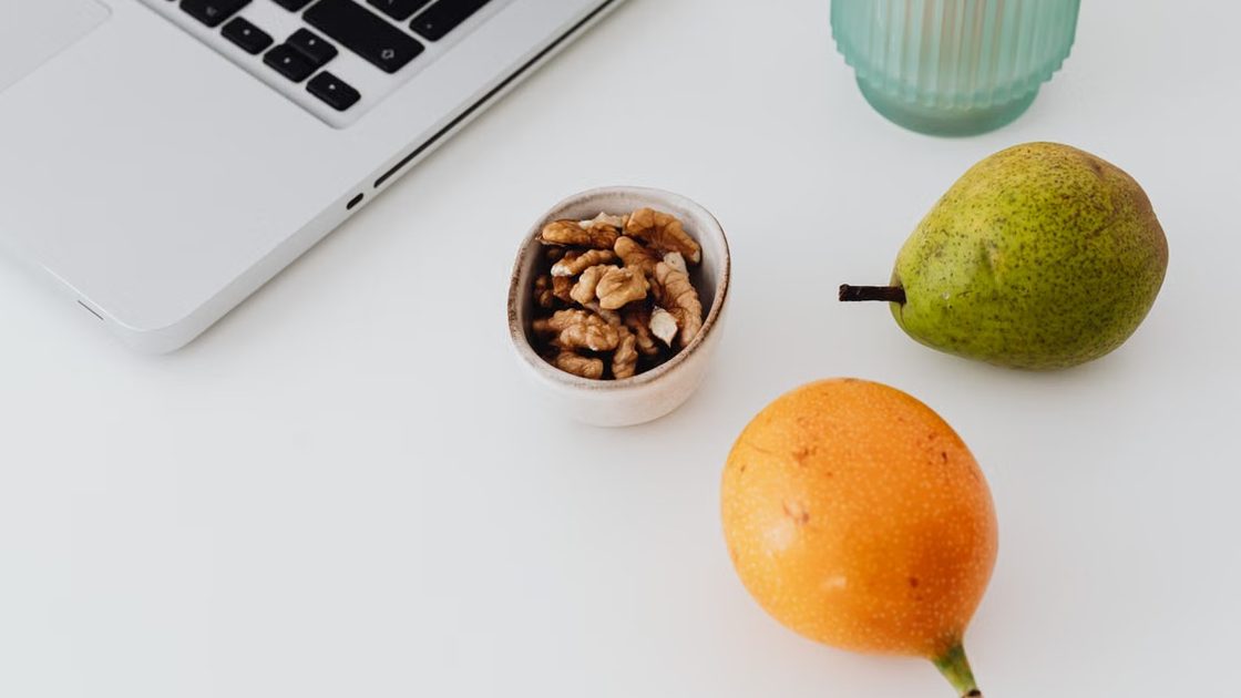 Mesa de trabajo de nutricionista con portátil, fruta y frutos secos